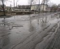 Покрытие улицы разрушено полностью, на улице много луж под которыми большие ямы.