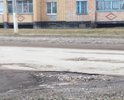 Дорога с большим количеством ям. Автомобили на некоторых участках объезжают по газонам. Засыпка крупным щебнем некотрых ям не помогла