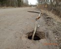 Данный отрезок дороги, достаточно давно имел асфальтное покрытие. Около 5 лет назад, его засыпали щебнем,гравием и песком,с тех пор в сухую погоду от передвижения по данной дороге поднимаются клубы пыли, что очень мешает жителям близлежащих домов, а так же на некоторое время затрудняет обзор водителям. Передвижение в любое время года возможно со скоростью 5-25 км/ч из-за ям, выбоин, напоминающих стиральную доску. Защитные полосы вдоль водоема отсутствуют, в силу этого в зимнее время автомобили с дороги съезжали в водоем.Периодическая грейдеровка помогает лишь на 2 недели. Этой весной, непосредственно около водоема случился обвал грунта прямо на проезжей части, что является не безопасным для движения транспортных средств.