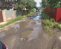Проезд с огромной лужей и полностью разбитым асфальтом по улице Железнодорожная.
