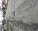 Улица с оживленным движением. Большое количество грузовиков проезжает ежедневно. Там, где есть на дороге асфальт, он проминается (так как положен над трубой), превращая дорогу в подобие волн. То, что не становится волнами, превращается в ямы с острыми краями. Глубина ям не была измерена, на взгляд близка к 10 сантиметрам и более. Указанный участок улицы усыпан щебнем, выбивающимся из ям. Колеса легковых машин попадание в ямы не выдерживают, образуются "шишки". Говоря же о грузовиках, попадающих в эти ямы, то они бьют с такой силой, что внутри дома трясутся вещи, шкафы, предметы, висящие на стенах, и окна.