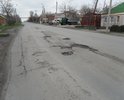 Улица с оживленным движением. Большое количество грузовиков проезжает ежедневно. Там, где есть на дороге асфальт, он проминается (так как положен над трубой), превращая дорогу в подобие волн. То, что не становится волнами, превращается в ямы с острыми краями. Глубина ям не была измерена, на взгляд близка к 10 сантиметрам и более. Указанный участок улицы усыпан щебнем, выбивающимся из ям. Колеса легковых машин попадание в ямы не выдерживают, образуются "шишки". Говоря же о грузовиках, попадающих в эти ямы, то они бьют с такой силой, что внутри дома трясутся вещи, шкафы, предметы, висящие на стенах, и окна.