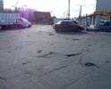 На площади между трёх сетевых магазинов - открытая парковка для покупателей. Дорожное покрытие проездов к парковке со всех трёх сторон - во множестве ям.