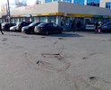 На площади между трёх сетевых магазинов - открытая парковка для покупателей. Дорожное покрытие проездов к парковке со всех трёх сторон - во множестве ям.