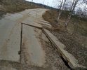 Покрытие дорожными плитами. Часть плит подмыло ручьем и одна плита сильно просела. По этой дороге люди возят детей в школу и дет.сад, ездят на работу, т.к. автобусного сообщения нет. Если так и оставить, плита под чьим нибудь автомобилем провалится совсем. Аварийно опасный участок.