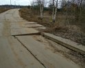 Покрытие дорожными плитами. Часть плит подмыло ручьем и одна плита сильно просела. По этой дороге люди возят детей в школу и дет.сад, ездят на работу, т.к. автобусного сообщения нет. Если так и оставить, плита под чьим нибудь автомобилем провалится совсем. Аварийно опасный участок.