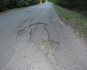 Разбитая пригородная дорога. Опасность в близости пешеходной зоны.
