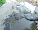 Огромная яма при въезде во двор. Въезд машинам затруднён. В яме всегда скапливается вода и грязь. Яме уже более 2-х лет. С каждым годом её размывает все глубже и шире. Так же пострадал тротуар вдоль этой дороги.