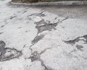 На участке Таврического проезда глубокие трещины, ямы и выбоины в асфальте; асфальт крошится и размывается.