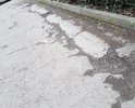 На участке Таврического проезда глубокие трещины, ямы и выбоины в асфальте; асфальт крошится и размывается.