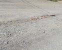 Дорога идет по уклону с горы. Снег, когда тает и дождь размывают щебенку на дороге. В данном месте колея (или русло ручья) настолько глубока, что пересекая дорогу машины "скребут брюхом". Попытки заложить яму кирпичами не помогают.