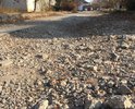 Дорога старая - участок не ремонтировался никогда. проезжают мимо машины - отлетают камни из-под колёс - бьют по стёклам и автомобилям. Проблема в дождь - камни с нашего участка - смывает на отремонтированную улицу Комсомольская - как следствие новая дорога резко дряхлеет.