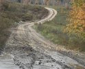Улица Подгорная. Жжелезнодорожный переезд под насыпью для легковых авто. Так как грейдер не может пройти под переездом улица не грейдеруется очень долго. Грунт. Мелкий камень, глина и почва. Ямы, канавы, колея частая. Частично есть супесь. Улица находится за железнодорожной насыпью. Покрытия нет вообще. Является жилой. Рядом расположена станция и магазины. Знаков нет. Необходима осыпка улицы и формирование дорожной подушки. Уместно все укласть бетонными плитами. Есть взгорки и уклоны, частично есть кустарник. местность неровная с сильными перепадами так как находится перед сопками. Возможно необходимо или углубить проезд для автомобилей то есть реконструировать для проезда грузовых авто чтобы грейдер мог по кратчайшему маршруту пройти под насыпью. Необходим ремонт проезда под насыпью укрепление по сроку эксплуатации.