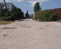 Разбитая дорога по ул. Десантников в пгт. Приморский. Старый асфальт, ямы. Отсутствует освещение и ливневая канализация. Также в плохом состоянии тротуар.
