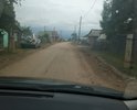 Улица Набережная грунтовая дорога. Состав грунта - песок. Узкая ширина. В зимнее время снег выпадает высотой около 1,5 метра и грейдер не может прочистить улицу. Зона посещения туристов и отдыха. По ней расположены причалы для лодок и гостевые домики. Улица сквозная ведет в конец поселка. Часто образуется дорожная рябь и ямы. Требуется асфальт в идеале. Уклон около 38 градусов. Часто размывается стоками с утеса требуется водосток с земляным фильтром. Требуется обновить земляные канавы для накопления дождевой воды. Вообще надо подумать над проектом. Выслал письмо такого характера:

Прошу обратить внимание в качестве перспективного участка под геодезические исследования дорожного полотна и песчаного основания под ним а так же гравия в селе Турка ( половинка). По испрашиваемому жителями ремонту дороги по улице Кирова и Набережной грунт соответствует ГОСТу ( Дорожные одежды песчаные). Поэтому разумно будет провести экспертизу участков и имея акт на руках пересчитать стоимость земляных работ на уменьшение. В данном случае около 70% проездов и дорог там будут соответствовать ГОСТу песчаные насыпи, что позволит сумму экономии передвинуть на проектирование каскадной ( мое предложение) водосливной системы проходящей по трубам под мостиками ( на них же и делать каскад) по земляным канавам. Земляные канавы остались со времен СССР и их необходимо заактировать и определить степень разрушения. При устройстве своим способом ( хозспособ возможность использовать 25% сметы на самозанятых на таких земляных работах согласно Закона РФ). Перед проездами, где пробегают талые воды считаю следует рассмотреть вопрос устройства бетонированных колодцев с проложенной трубой над потоком и проходящей дальше в такую канву. Такая канава ( слои дробленка, глина, песок, глина, дробленка более точный гост может подсказать проектировщик) станет дешевле для бюджета дорожного фонда и позволит направить средства на строительство двухсекционных песчаных фильтрационных резервуаров в конце ПОЛОВИНКИ и в местах определенных по водостокам вдоль дороги. При этом накопитель делается выше а потом отделяется фильтром земляным крупнозернистый песок с сердцевиной из дробленки и слой сверху мелкозернистого песка). То есть у нас будет природная фильтрация но в искусственном сооружении при этом техника может использоваться собственная, что позволит удешевить расходы. Такая схема может служить у нас типовой с различными вариациями по запросам жителей на сходах и в болотистых местностях. Канавы между желательно сообщать трубами под дорогой. При каскадном решении вода не переливается через край канав и не создается стремнинный поток при сильных осадках и система регулирует себя сама и с нее возможно осуществлять полив огородов. Поток создается в таком случае медленный и система не переполняется при диаметре труб на 70% больше площади сечения канвы. Канавы для удобства изготовления могут быть треугольными или полукруглыми или трапециевидными. Скат с горы проектируется бетонированный с устройством ребер тормозящих потоки с горы. При устройстве перил целесообразно рассмотреть использование габионов так как там есть свой камень и при устройстве столбиков это может проходить как капстроение и придаст колорит и необычный вид потом дороге на мостиках и ограждении резервуаров таких. Трубы кроме того могут по сроку службы улучшаться путем накладки феном промышленным полимерного слоя и простоты ремонта диаметр необходим около 1 м.. Принять во внимание например устройство из габионов ( блоков или плит) сливы ( водостоки с гор и распадков) уложив их по руслам. Это даст возможность проходить транспорту и пешеходам не затрудняя движения а вода при этом большей частью будет протекать в габионах и исполнимо для главы СП Туркинское. Перед горой предусмотреть устройство заграждения из габионов что дешевле будет чем завоз бетона и бетонирование. Вместо мостиков предлагаю уложить по 2 трубы соединенных между собою цементным раствором это будет разделать потоки с распадков и уменьшать скорость потоков. Габионами можно уложить постепенно поэтапно русла таких распадков размывающих улицы по с. Турка в том числе заглубив русло миниэкскаватором. Вместо мостиков для придания единого архитектурного ансамбля уложить трубы и использовать старую дорожную одежду для отсыпки подъездов к дворам что снизит количество конфликтов и проблем. В трубах можно предусмотреть затворы для накопления воды в засуху для полива огородов и перила из габионов. Трубы так же могут прокладываться в таком случае через ручьи в конце улицы Кирова имеется ручей. Что полностью будет соответствовать требованиям Водного кодекса и экологически чистому использованию разных вид вод в последующем и не создаст неприятностей с Роспотребнадзором. Предусмотреть укладку георешетки и холодной асфальтной мастики на проезжую часть это упростит укладку асфальта в холодное время. В целом такой подход позволит увеличить протяженность сделанной улицы. Обращаю внимание что мастика продавливается со временем и там необходимо укладка 1 слоя дробленки под мастикой.
  Данный подход будет применим и для Гремячинска и для Горячинска учитывая что там очень сложно с устройством АБЗ и варки горячего асфальта.